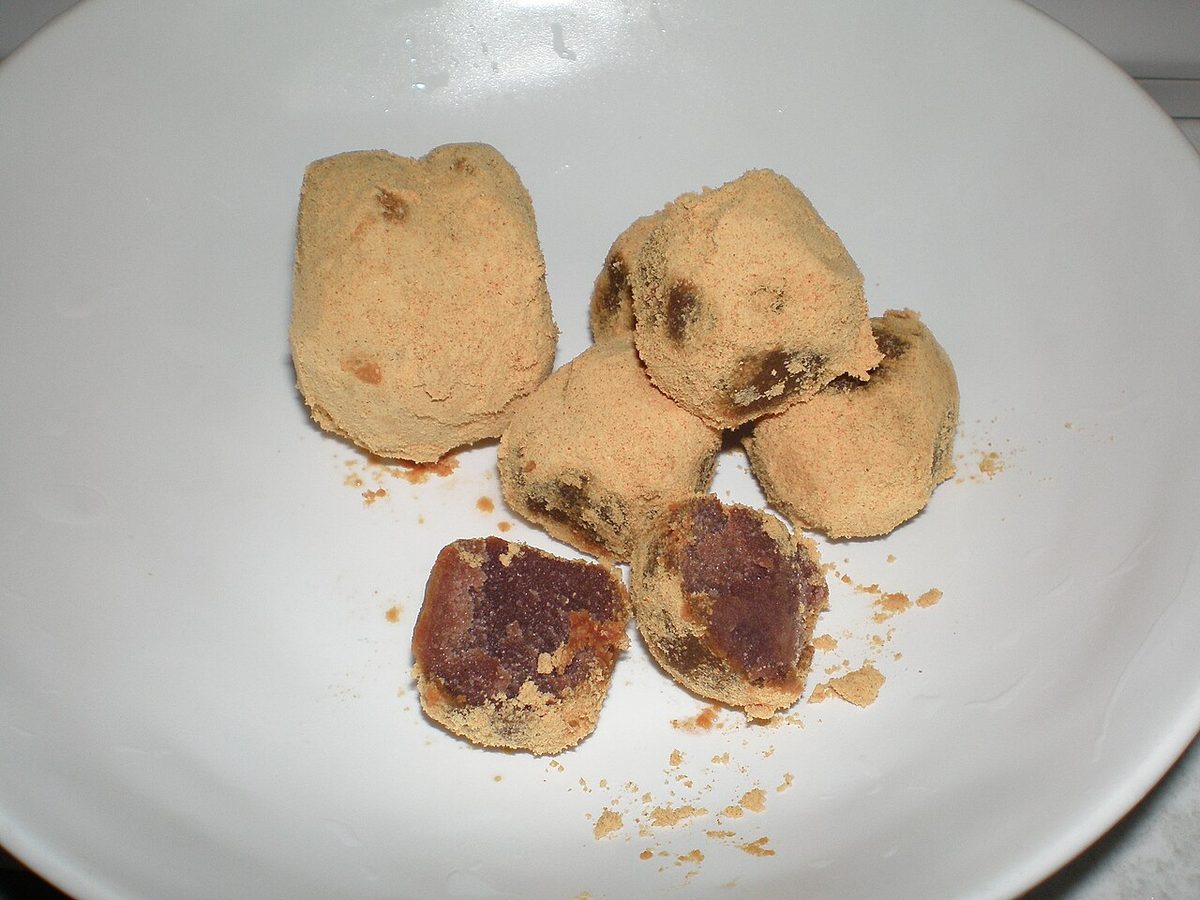 Kinako-dusted cubes of dark red-bean anko paste in a white bowl, one piece broken open