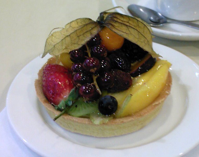 Glazed fruit tartlet topped with strawberry, kiwi, mango, blackcurrants, blackberry, and physalis